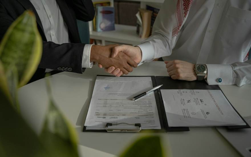 Deux personnes se serrent la main au-dessus d'un document