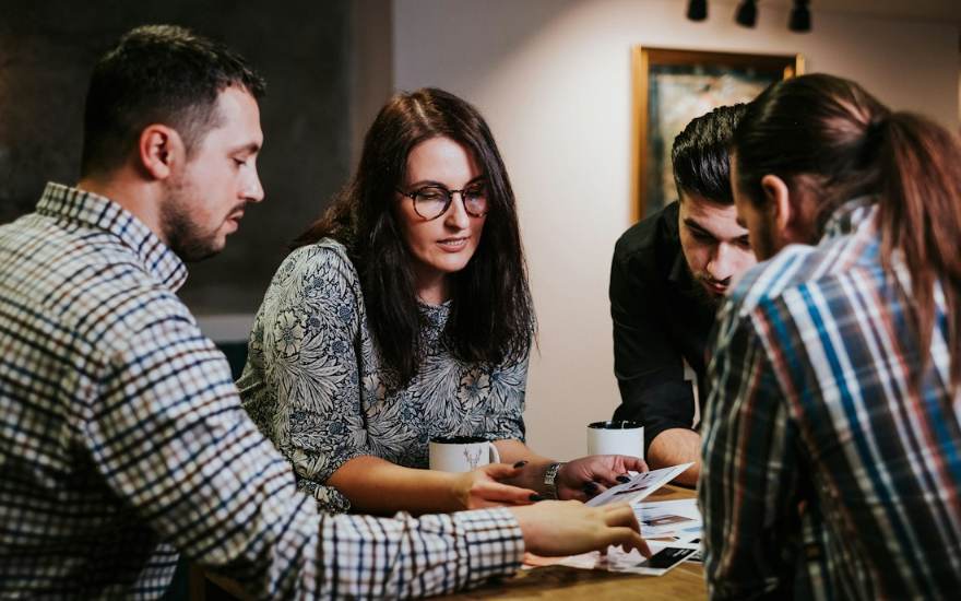 Quatre collègues examinent des documents autour d'une table