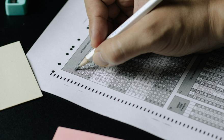 Une main remplit une grille de réponses au stylo