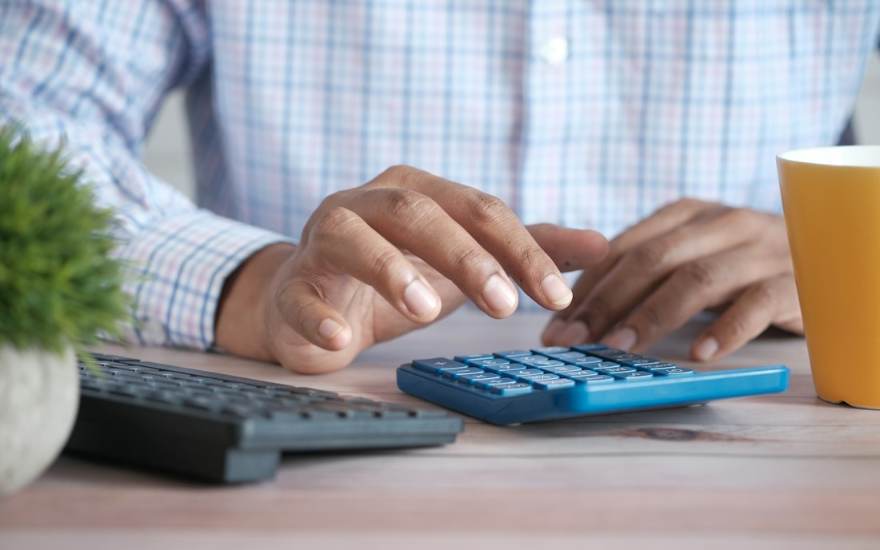 Une personne utilise une calculatrice à son bureau